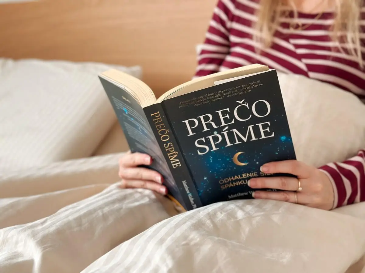 Žena čítajúca knihu Prečo spíme v posteli.