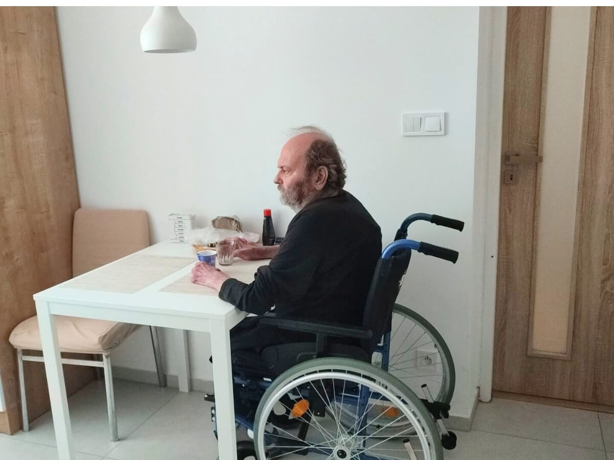 Invalidný dôchodca na vozíku za stolom.