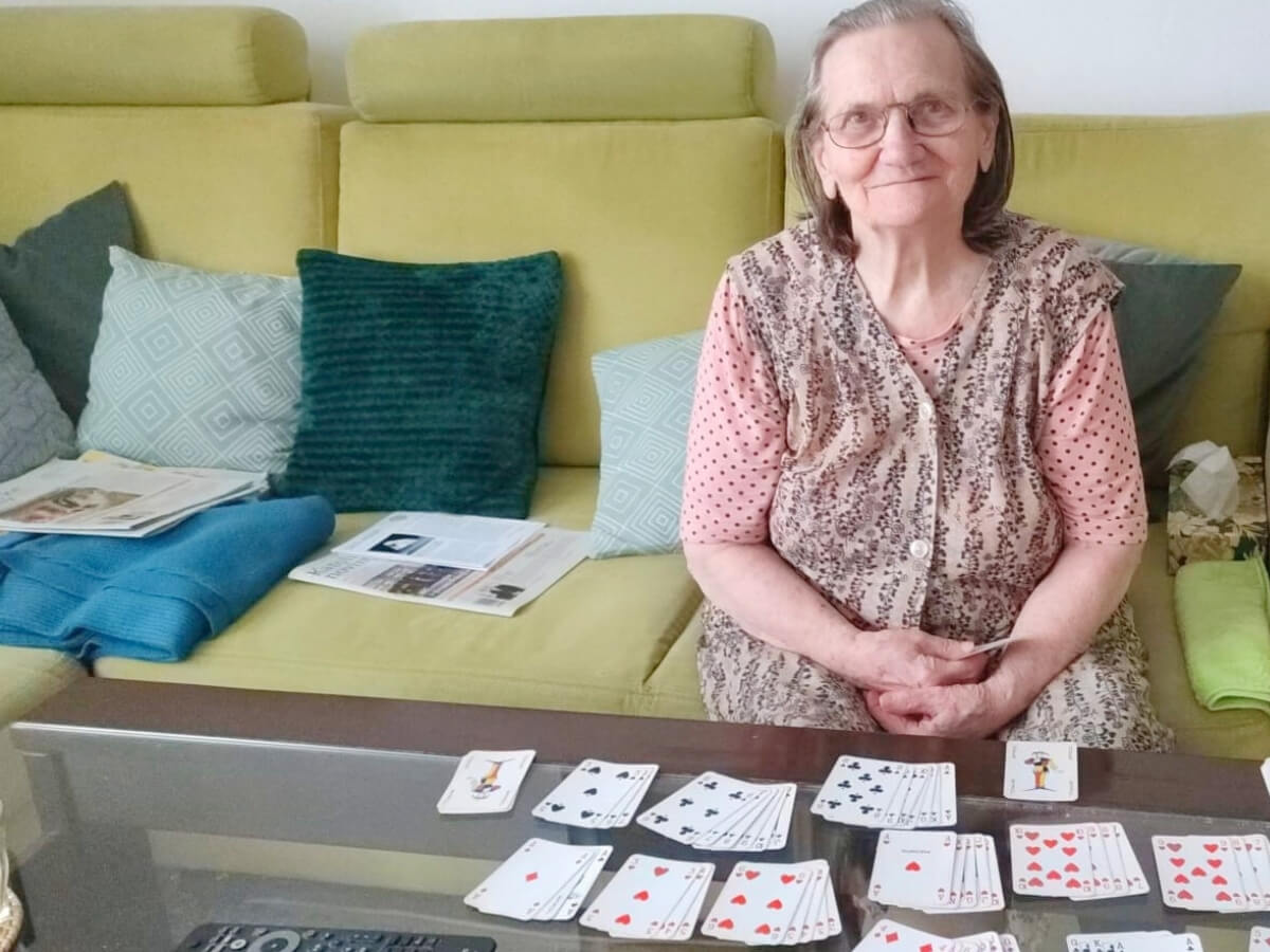 Dôchodkyňa hrá karty v obývačke.
