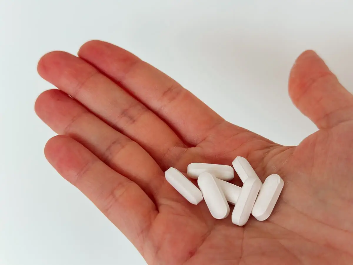 Tabletky melatonínu položené na dlani.