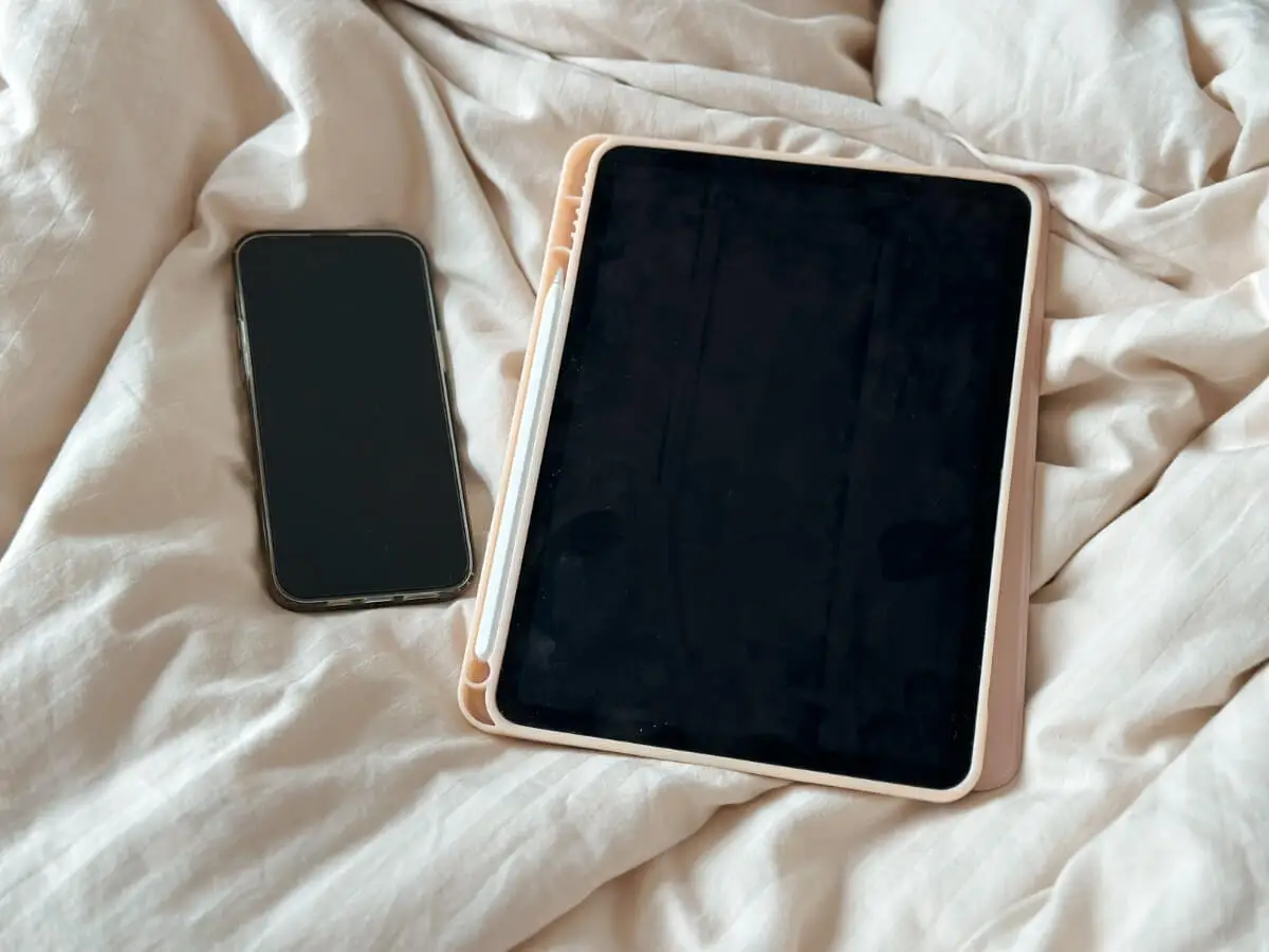 Smartfón a tablet položené na posteli.