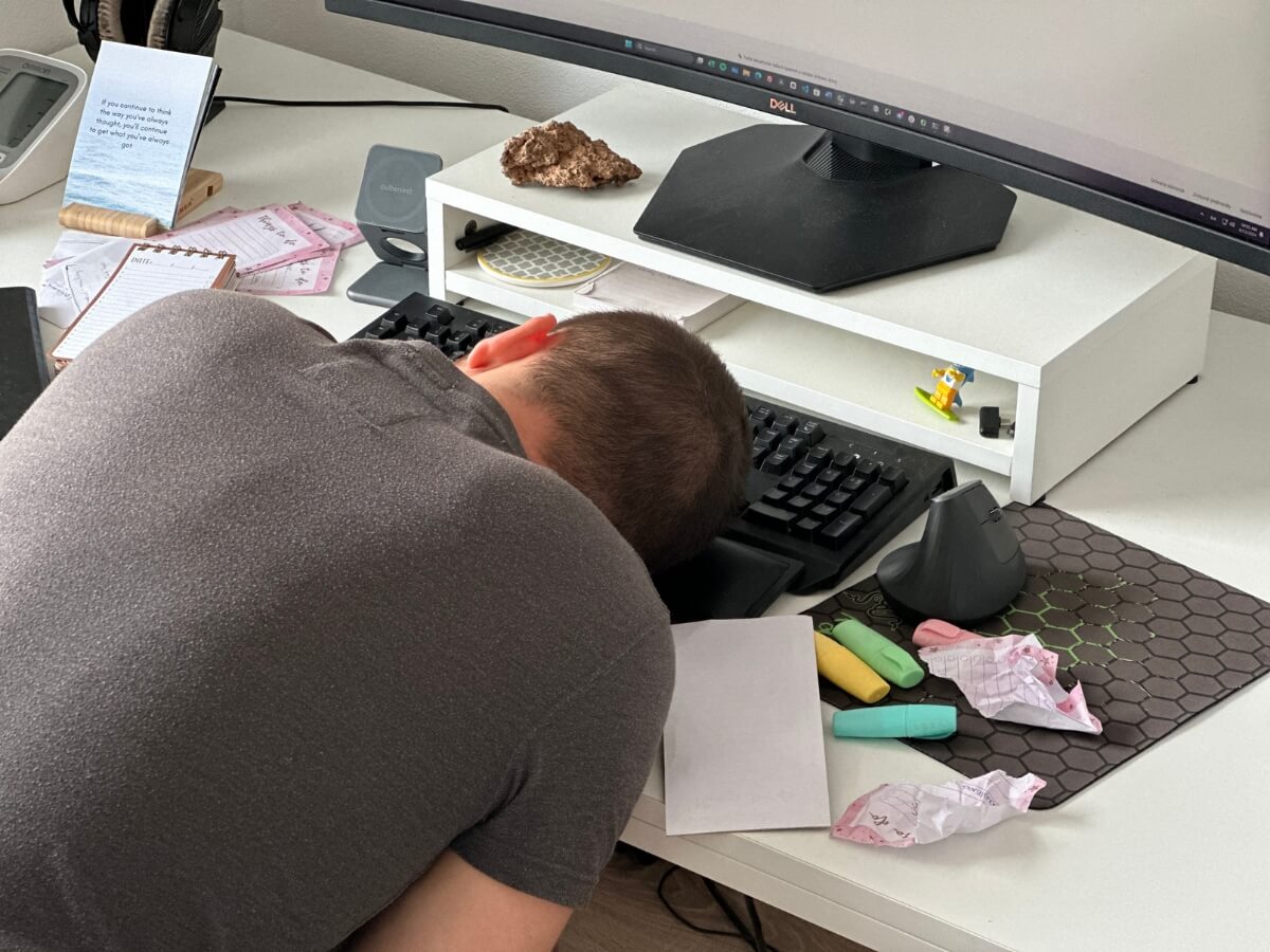 Muž spí opretý tvárou o klávesnicu pred počítačom.